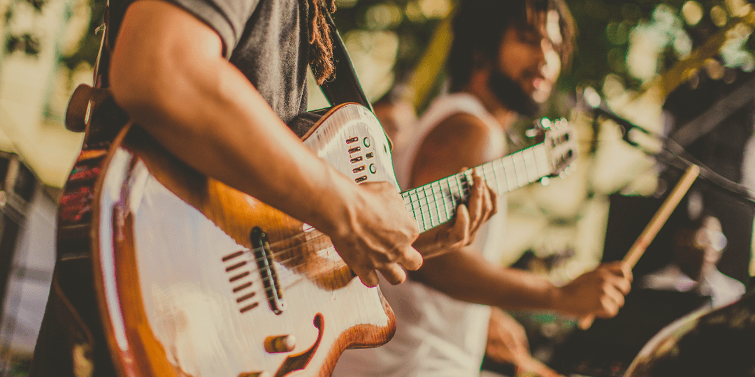 Musicians performing on stage, focusing on guitar and drums amidst a vibrant atmosphere