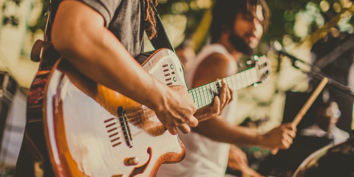 Musicians performing on stage, focusing on guitar and drums amidst a vibrant atmosphere