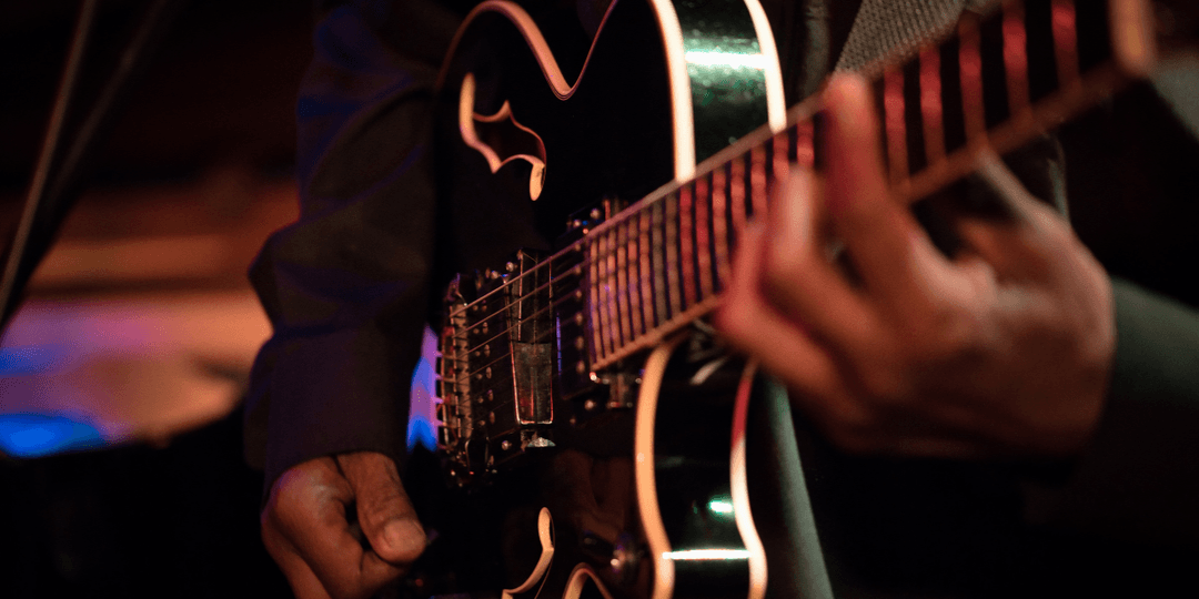 Close-up of a musician playing an electric guitar on stage with vibrant lighting