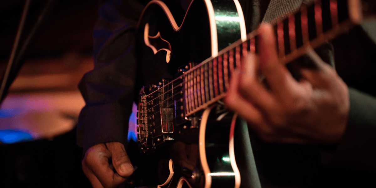 Close-up of a musician playing an electric guitar on stage with vibrant lighting