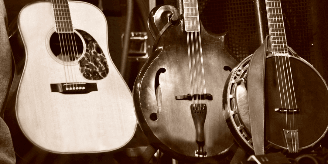 Three string instruments lined up: an acoustic guitar, a mandolin, and a banjo