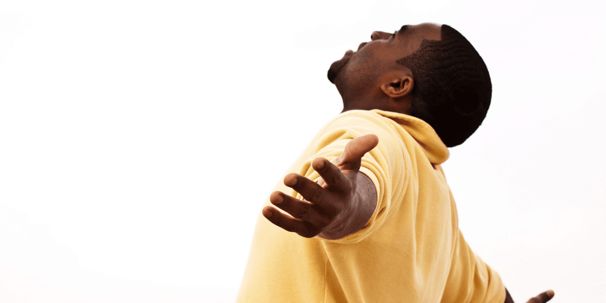 A man in a yellow polo shirt with arms outstretched and head tilted back