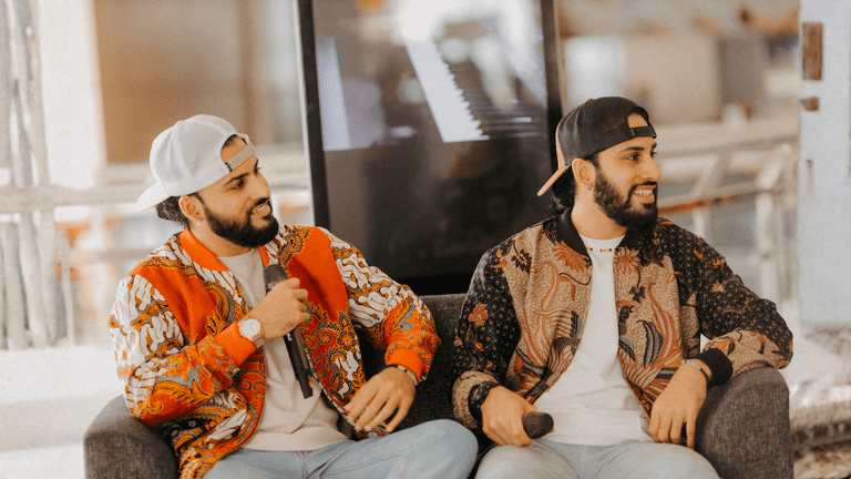 JJ Twins sitting together with microphones, smiling during an interview, representing their R&B and Hip Hop musical journey.