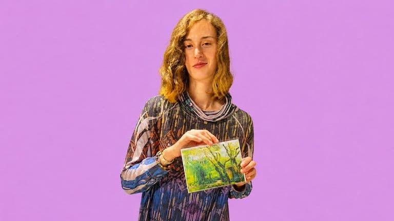 Tomiko Kausal-Hayes holding a colorful nature art print against a purple background.