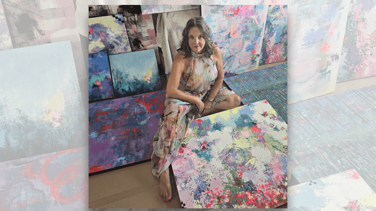 Lisa Wommack in her studio surrounded by vibrant abstract paintings.
