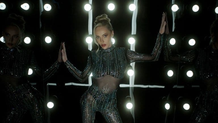 Brook Lynn shines in a dazzling mirror-lit moment, embodying empowerment and resilience in her music journey.