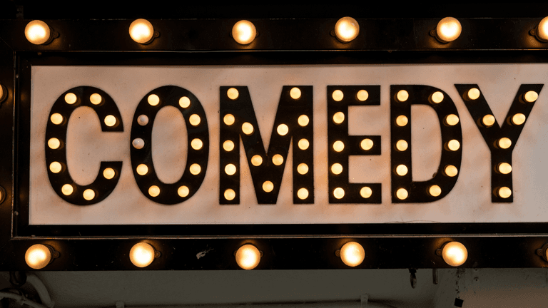 Comedy marquee sign illuminated with vintage-style light bulbs.
