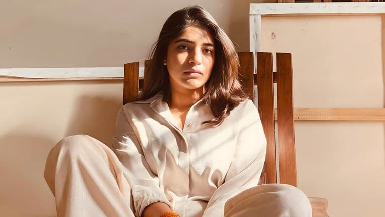 The image features Noor Diwan Goyal, an abstract artist, sitting in a relaxed pose, reflecting deep emotion and introspection.
