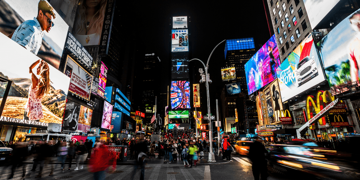 Vibrant Times Square at night, bustling with crowds and illuminated advertisements.