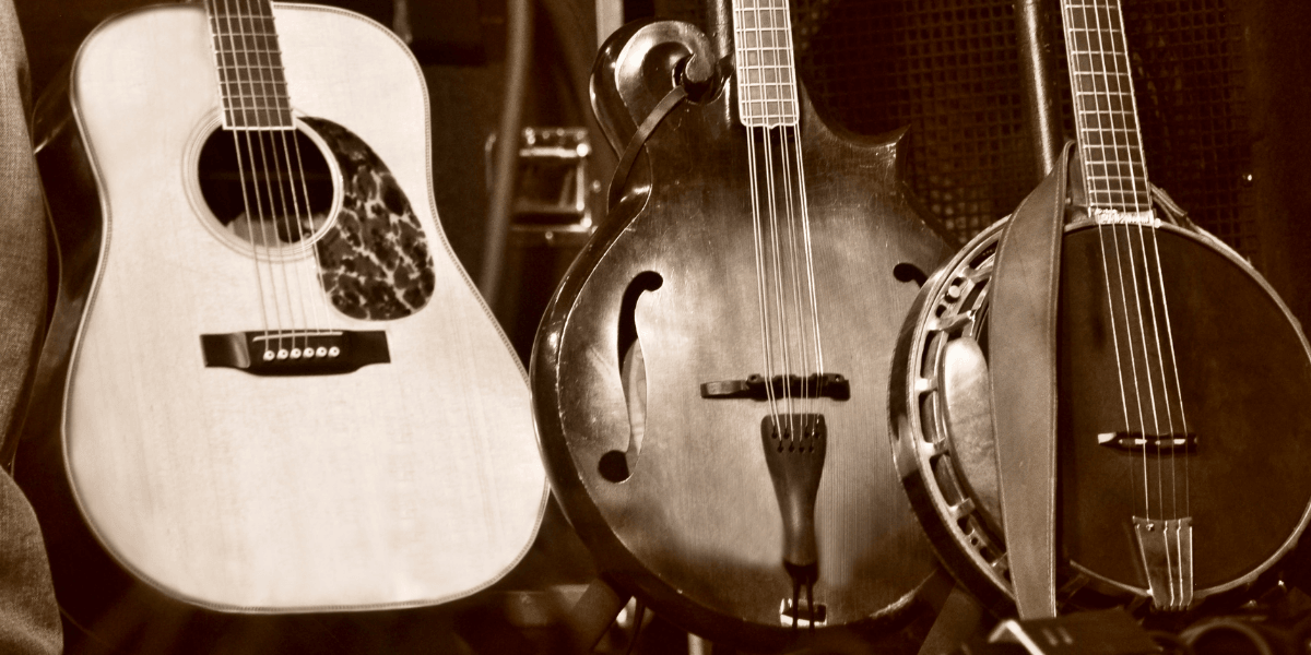 Three string instruments lined up: an acoustic guitar, a mandolin, and a banjo