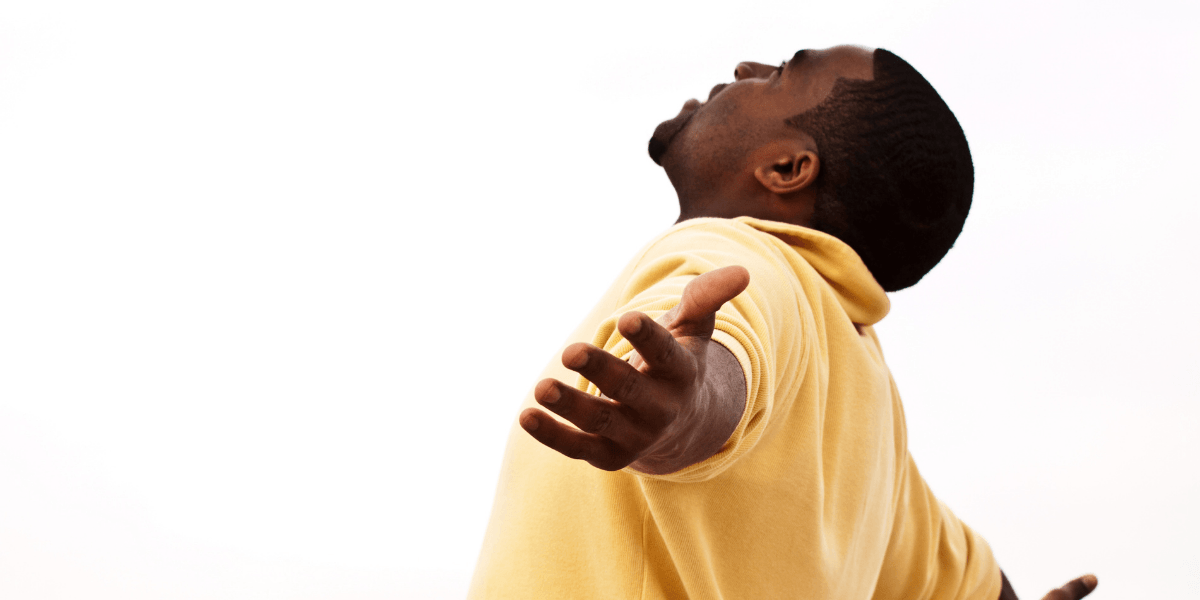 A man in a yellow polo shirt with arms outstretched and head tilted back