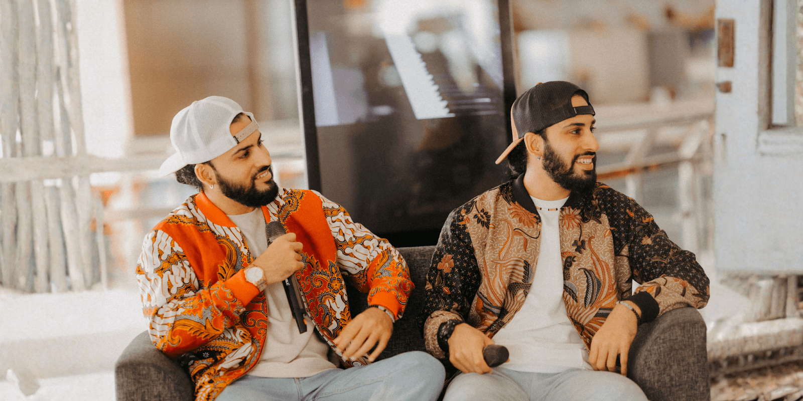 JJ Twins sitting together with microphones, smiling during an interview, representing their R&B and Hip Hop musical journey.