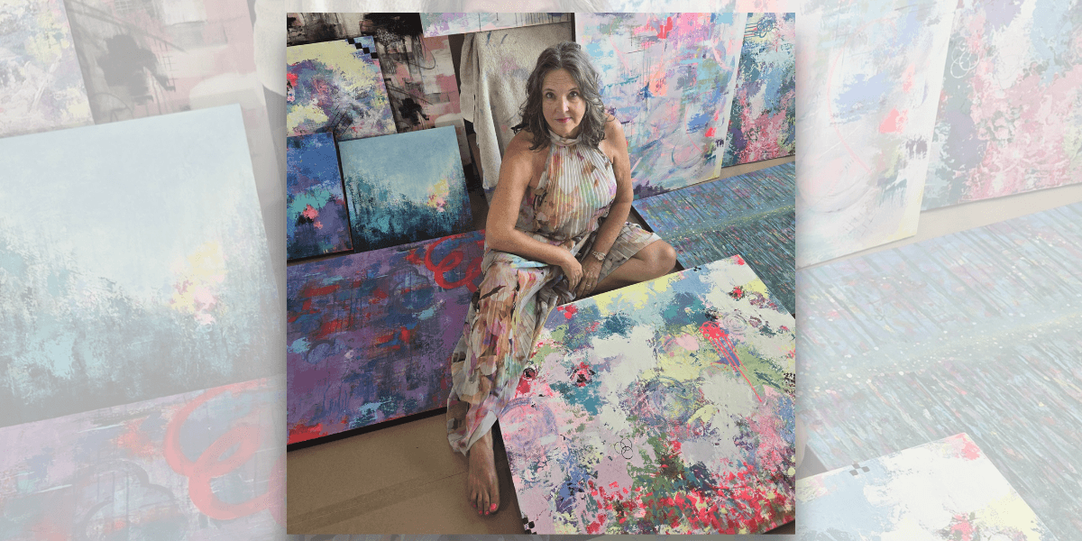 Lisa Wommack in her studio surrounded by vibrant abstract paintings.