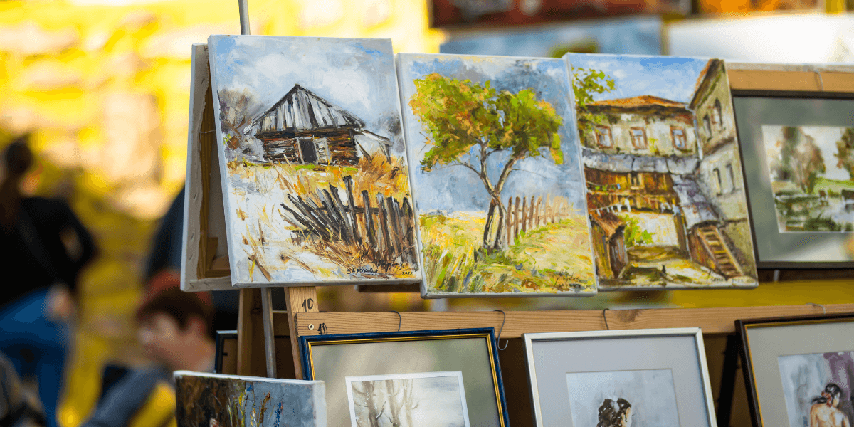 Landscape paintings displayed on outdoor easels at the Ann Arbor Art Fair.