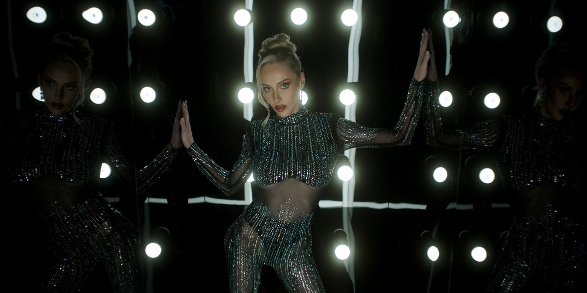 Brook Lynn shines in a dazzling mirror-lit moment, embodying empowerment and resilience in her music journey.