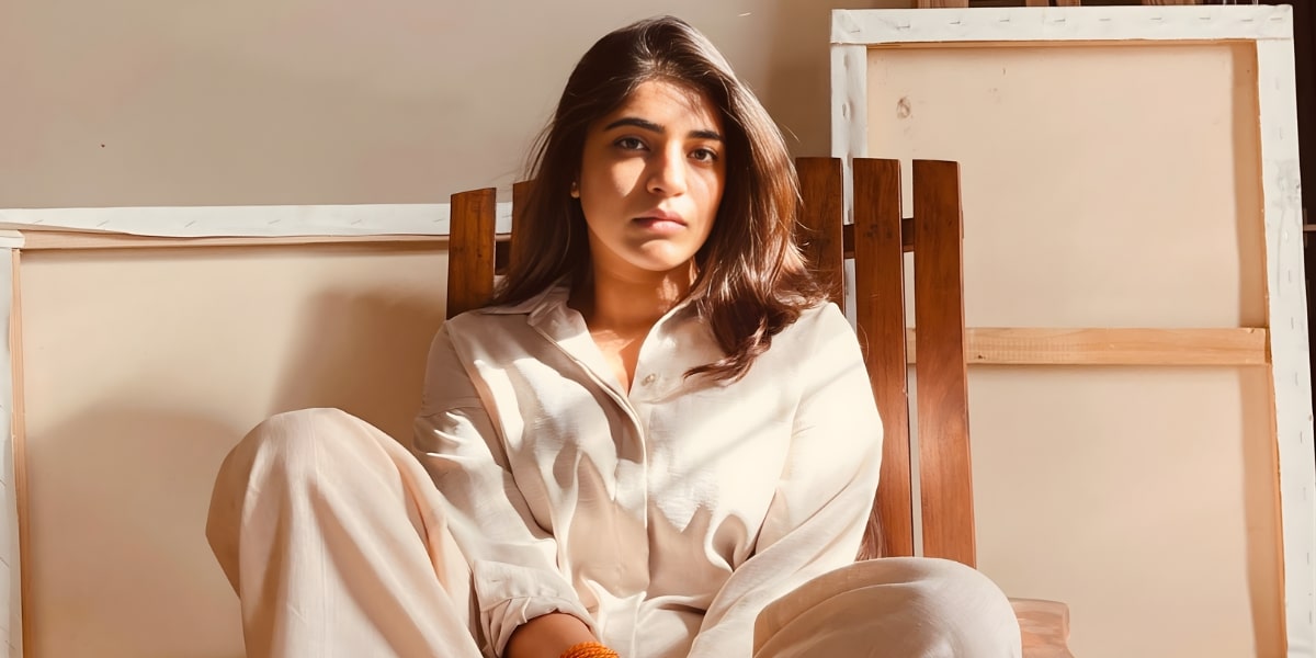 The image features Noor Diwan Goyal, an abstract artist, sitting in a relaxed pose, reflecting deep emotion and introspection.