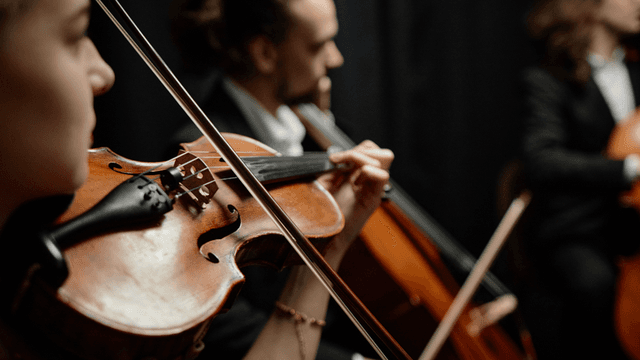 Close-up of musicians playing violin and cello in a dimly lit setting