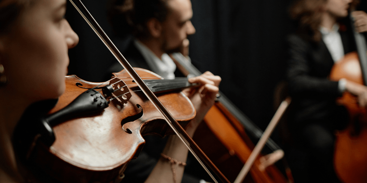 Close-up of musicians playing violin and cello in a dimly lit setting