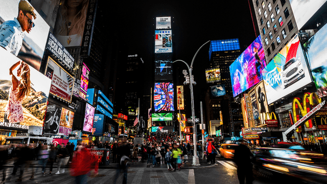 Vibrant Times Square at night, bustling with crowds and illuminated advertisements.