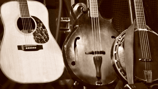 Three string instruments lined up: an acoustic guitar, a mandolin, and a banjo