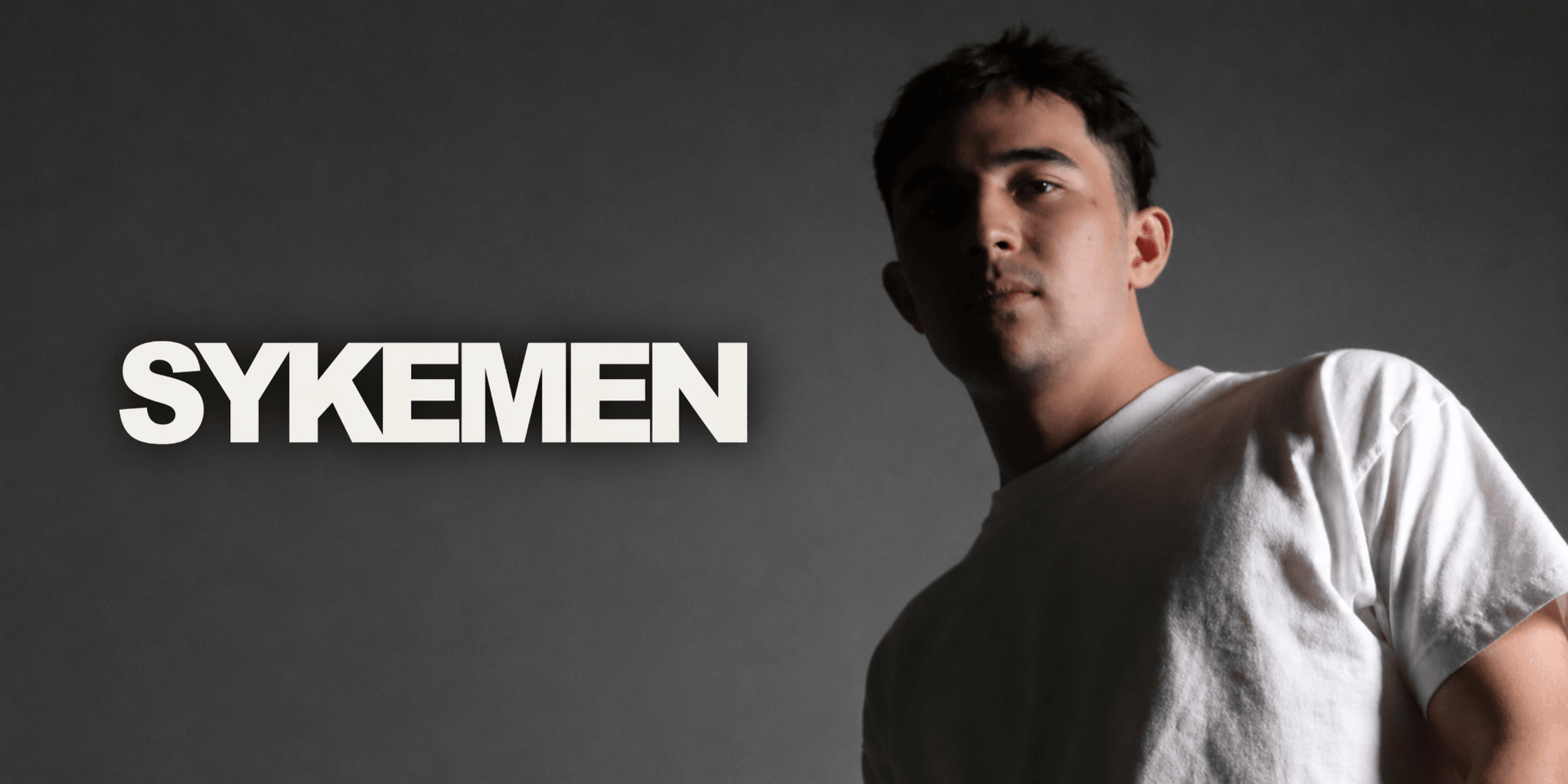 A young man in a white shirt poses against a dark background with stylized text.