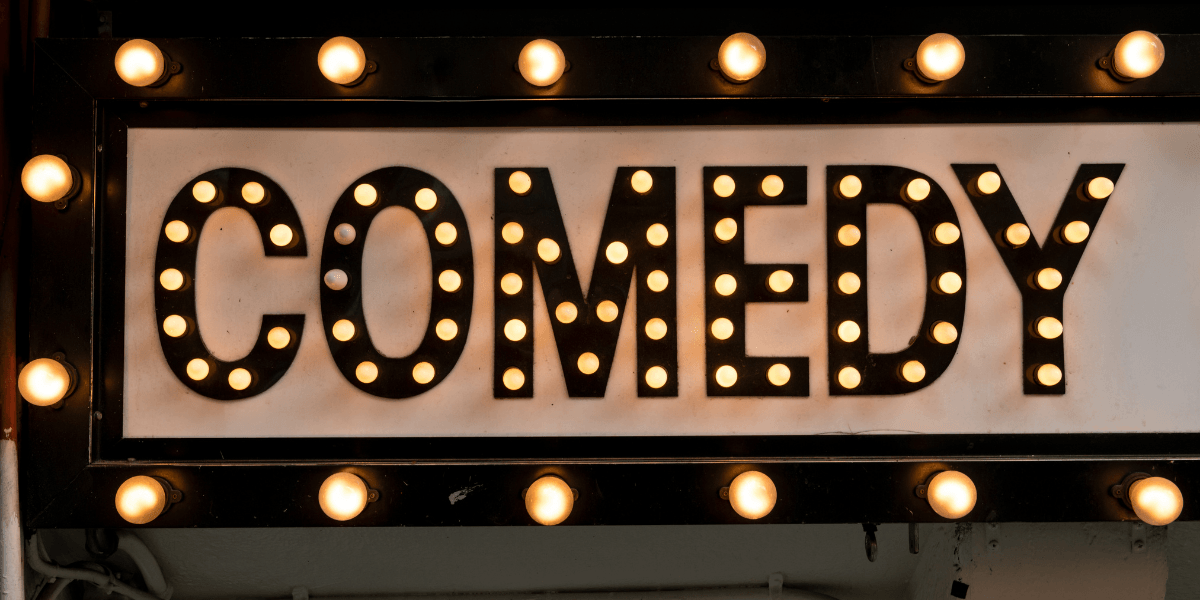 Comedy marquee sign illuminated with vintage-style light bulbs.