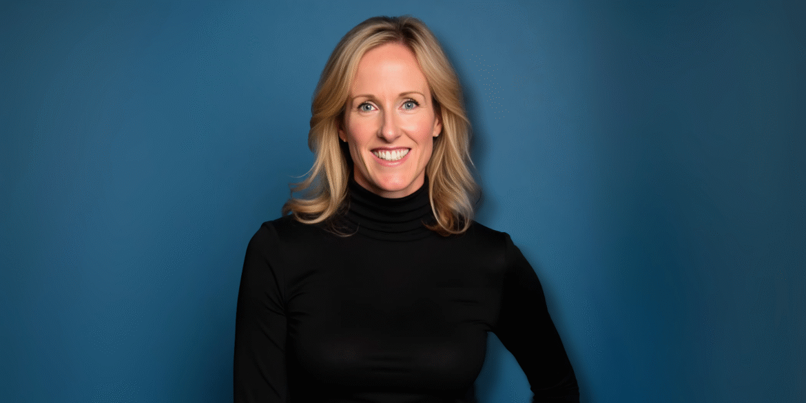 Erica Haupert smiling in a black turtleneck against a solid blue background.