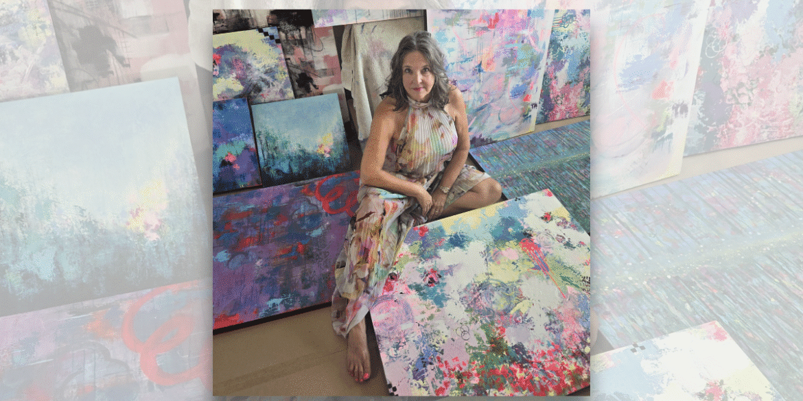 Lisa Wommack in her studio surrounded by vibrant abstract paintings.