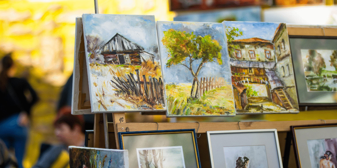 Landscape paintings displayed on outdoor easels at the Ann Arbor Art Fair.