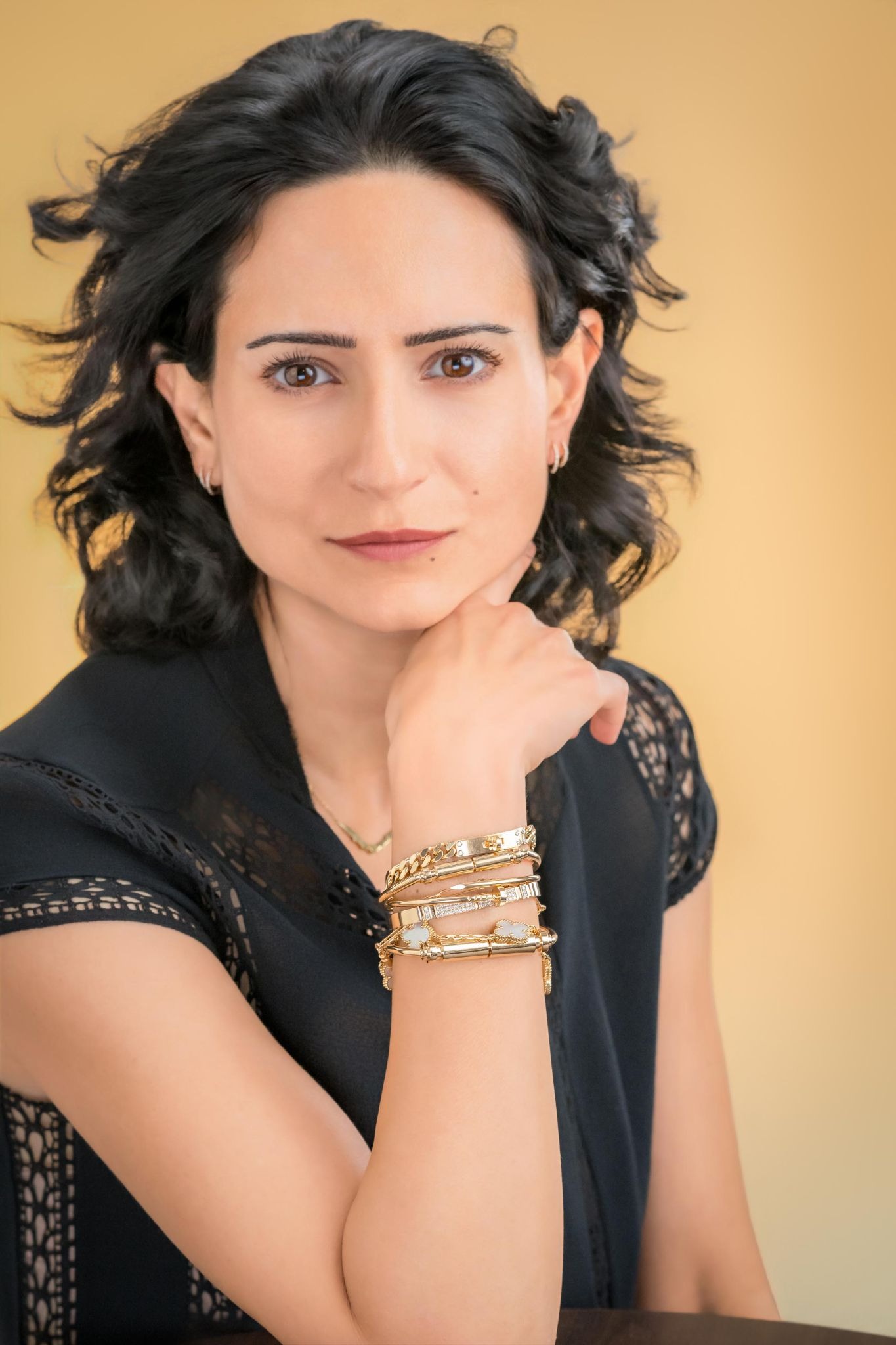 Elle Pirmoradi wearing black attire and gold Bangelle bracelets in a portrait.